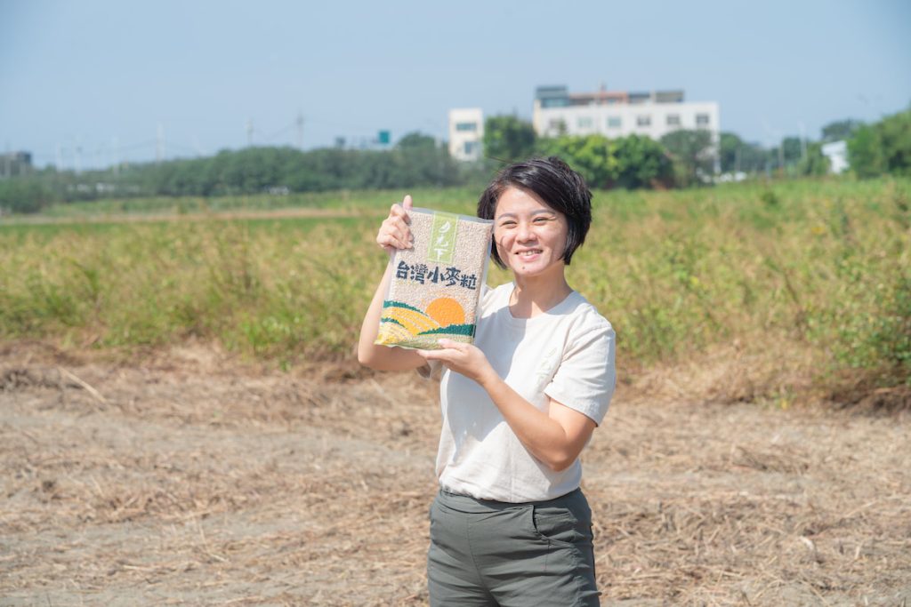 郭慧蟬手拿月光下出品的小麥粒，笑容燦爛。